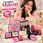 A woman applies makeup while surrounded by a large makeup combo set display on a table, including eyeshadow palettes, brushes, blush, foundation, lip products, and a pink makeup bag, with promotional text overlays.
