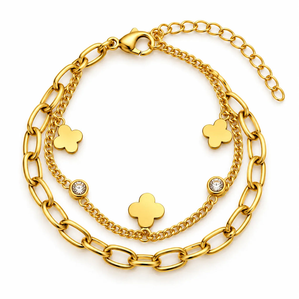A gold-toned multi-strand bracelet featuring a thick curb chain, a delicate chain with three clover motifs, and two bezel-set clear crystals, displayed on a clean white background.