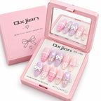 Pink press-on nail kit by Qxjian, showing an open compact with ten pastel artificial nails decorated with bows, polka dots, and plaid patterns, alongside the matching pink box.