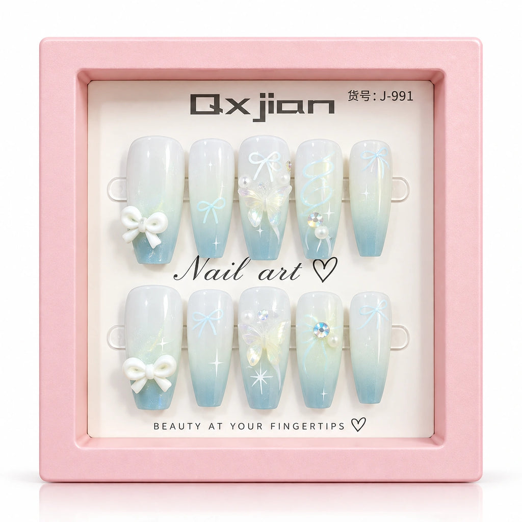 A set of 10 press-on nails displayed in a pink presentation box. The nails feature a light blue to white gradient with white bows, rhinestones, and delicate floral designs.
